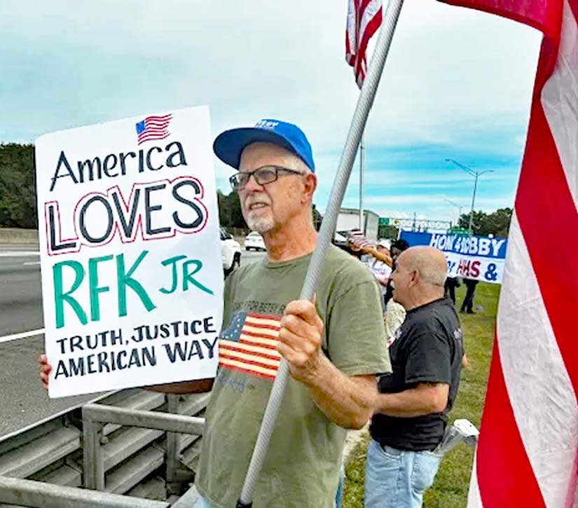 man holding flag and rfk poster