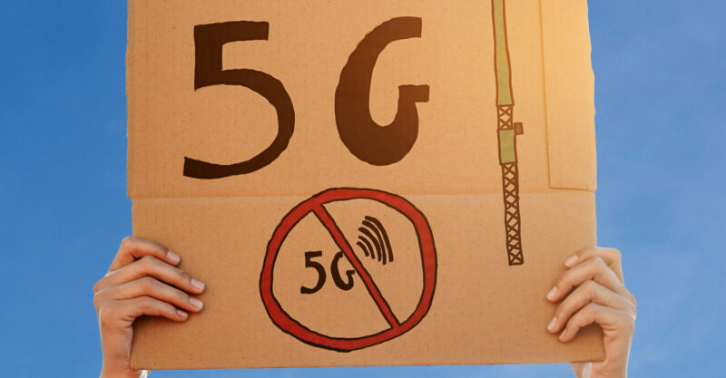 Woman holding sign showing 5g crossed out.
