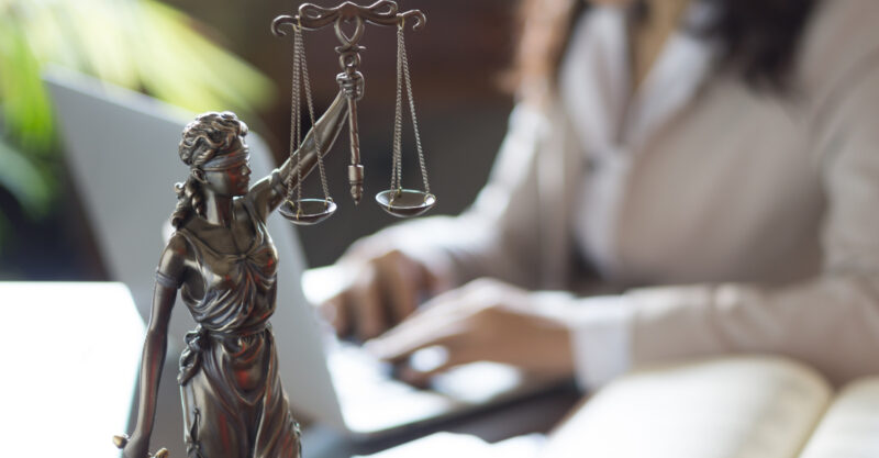 Statue of Justice and lawyer working on a laptop