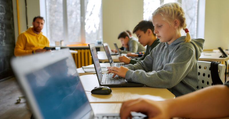Kids using laptops on their desks at school.