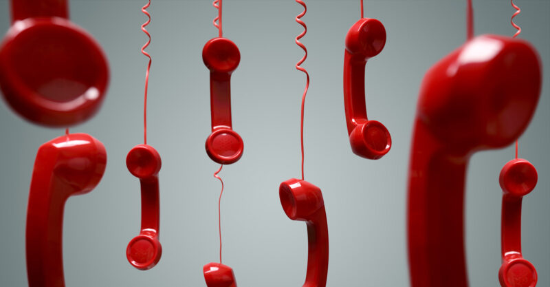 Red telephone receivers hanging by cords.