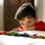 boy lining up a row of toy cars