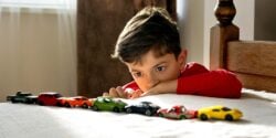 boy lining up a row of toy cars