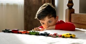 boy lining up a row of toy cars