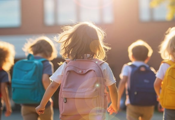 kids wearing backpacks walking towards a school