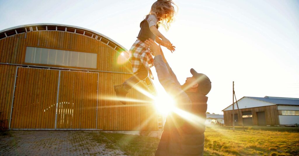 dad holding daughter on farm