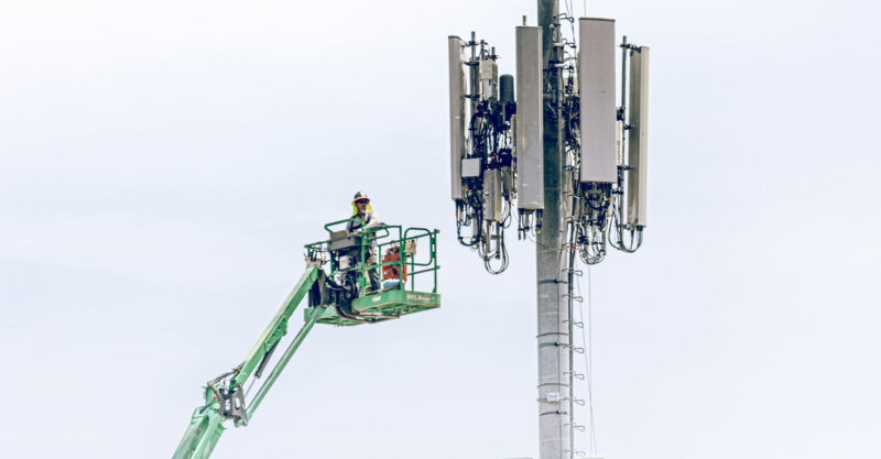 Worker on a lift next to a cell tower array.