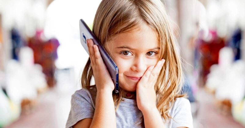 young girl holding cellphone to ear