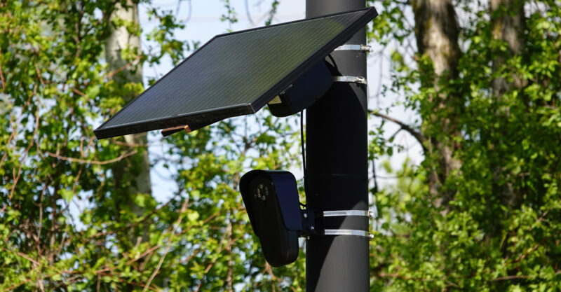 Flock safety police law enforcement license plate reader set up outside on pole to help catch vehicle speeders.