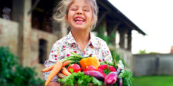 child holding basket of vegetables