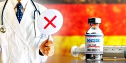 germany flag and covid vaccine with doctor holding up sign with "x" on it