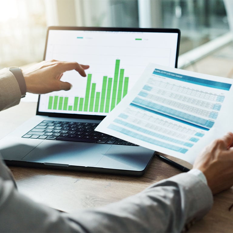 Man sitting at desk pointing to data chart on laptop computer