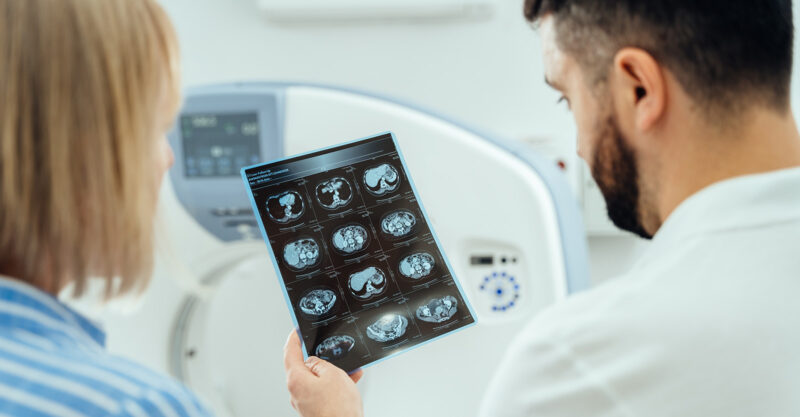 A man and a woman are looking at a medical image of a brain