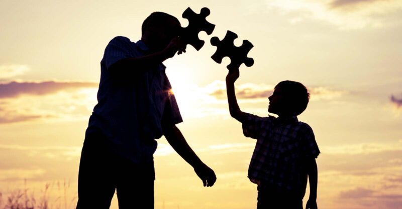 father and son holding puzzle pieces