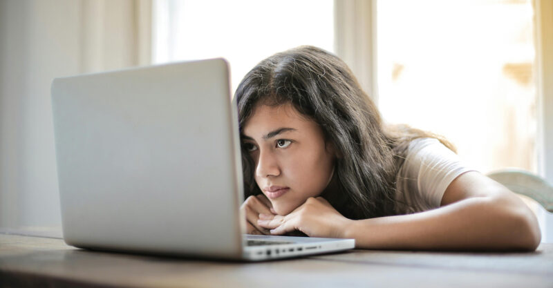 Young girl staring at laptop computer screen.