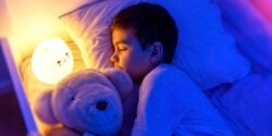 boy sleeping next to led night light
