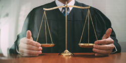 Male judge in a courtroom with the balance scale on wood table