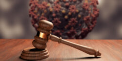 Judge gavel or law gavel on wooden table with coronavirus in the background.