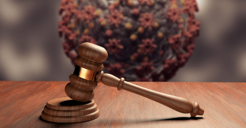 Judge gavel or law gavel on wooden table with coronavirus in the background.