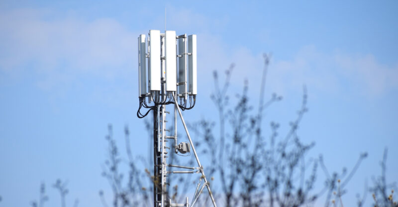 Photo of 5G tower in residential area behind tree tops.