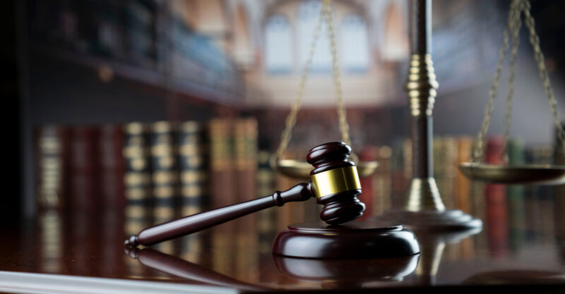 Gavel of the judge and the scale on court library background.