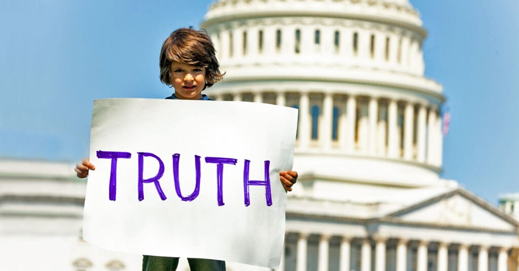 boy standing with truth sign