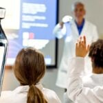 doctor teaching medical students and vaccine bottle