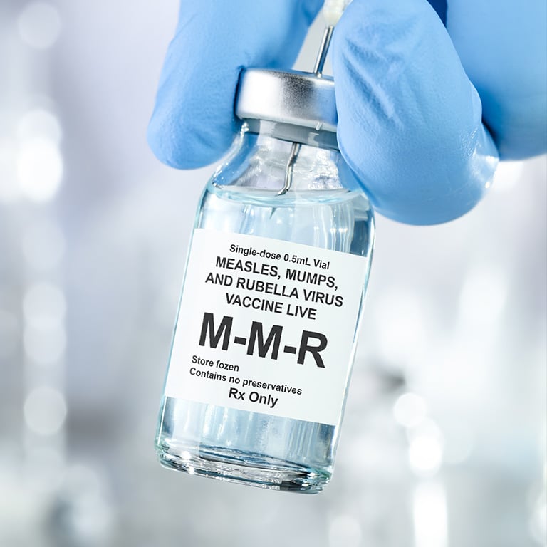 hand in blue medical gloves holding MMR, measles mumps and rubella, vaccine vial and syringe needle