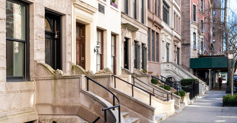 Empty sidewalk in front of old brownstone buildings in the Upper East Side neighborhood of Manhattan in New York City.
