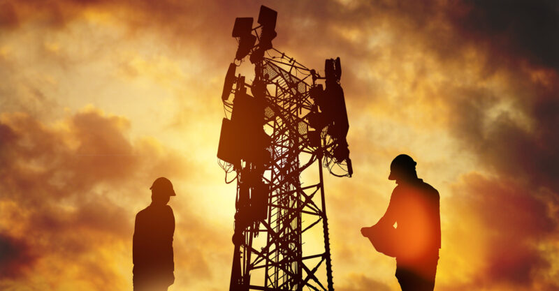 Silhouette Engineer worker man and woman working wearing helmets doing field work telecommunication tower holding blueprints controlling installation connectivity equipment maintaining 5G