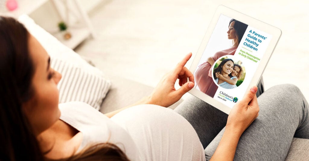 pregnant woman holding tablet with chd e-book on screen