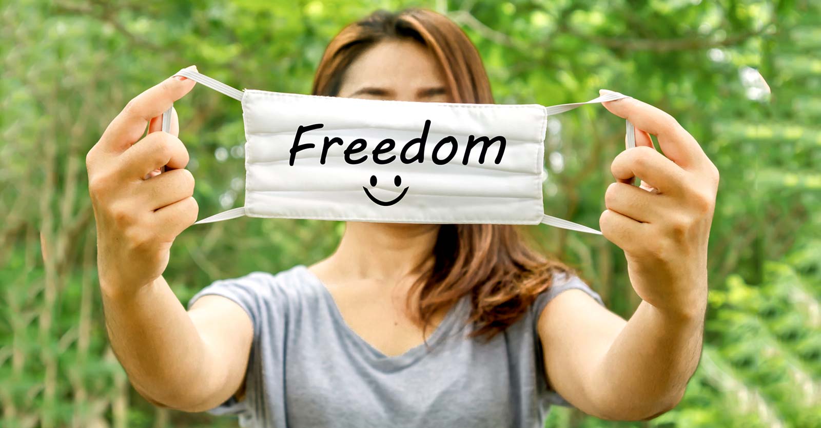 woman holding face mask with word "freedom" on it