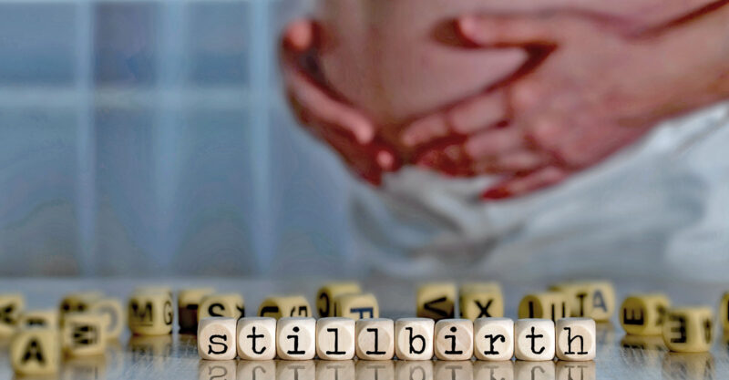 woman holding her belly with block letters stillbirth underneath