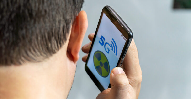 Man holding cell phone close to head with a radiation symbol on the phone screen