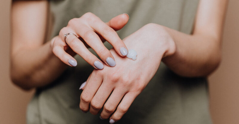 Woman applying personal care skin lotion to her hand.