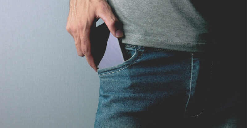 Photo of man putting cell phone in front pants pocket