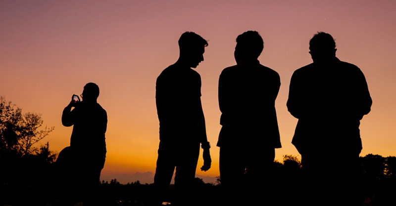 A group of men talking outside at sunset