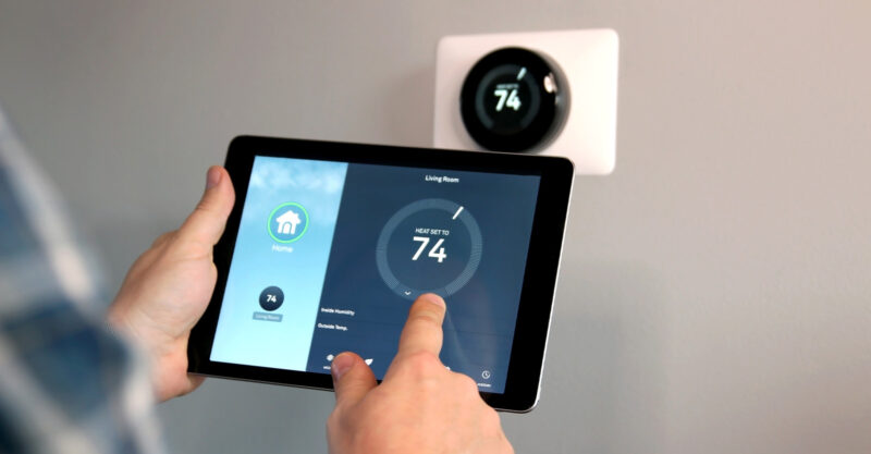 Man is Adjusting a temperature using a tablet with smart home app in modern living room