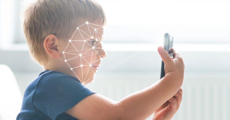 Concept photo of child holding a smart phone with face scan.