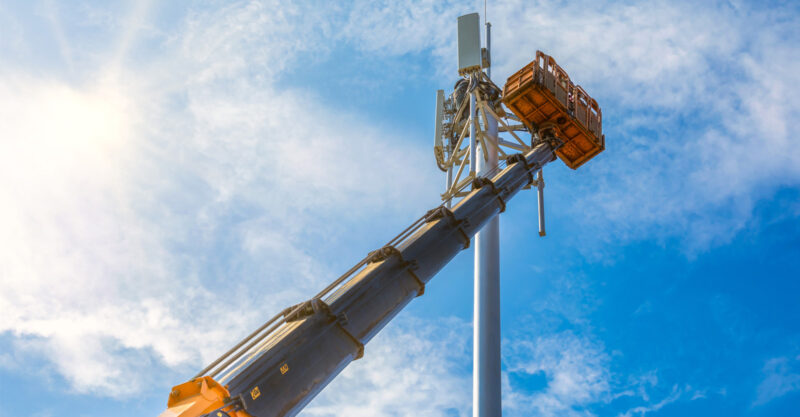 Photo of a crane arm lifted to a cell tower for installation of 4G and 5G.