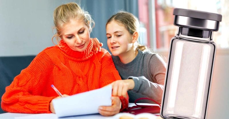 mom and daughter reading a form and a vaccine bottle