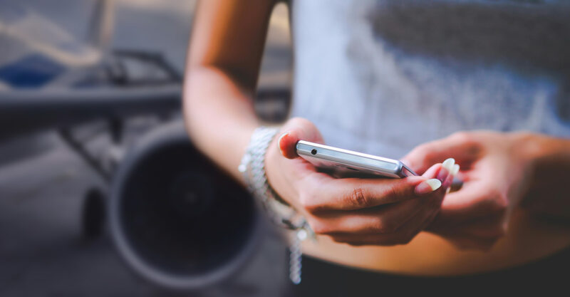 A woman using a smart phone with jet airplane in the background